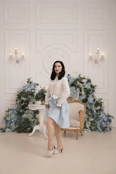 Mujer encantadora en retro lindo vestido de algodón posando en el interior de su apartamento blanco. Señora de la moda en traje vintage con medias . — Foto de Stock