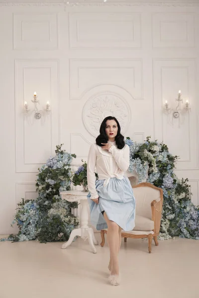 Mulher encantadora em retro bonito vestido de algodão posando dentro de casa em seu apartamento branco. Senhora da moda em roupa vintage com meias . — Fotografia de Stock