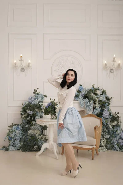 Mujer encantadora en retro lindo vestido de algodón posando en el interior de su apartamento blanco. Señora de la moda en traje vintage con medias . — Foto de Stock