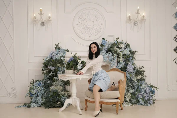 Mujer encantadora en retro lindo vestido de algodón posando en el interior de su apartamento blanco. Señora de la moda en traje vintage con medias . — Foto de Stock