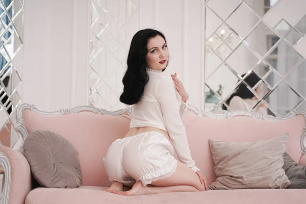 Υπέροχη μελαχρινή γυναίκα σε λευκό χαριτωμένο μπαρ ξεκούραση με ροζ καναπέ μόνο σε λευκό διαμέρισμα μόνο — Φωτογραφία Αρχείου