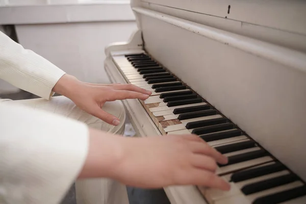 Eski beyaz kuyruklu piyano ile genç kollarını yakın. beyaz giysiler içinde kişi müzik çalar. — Stok fotoğraf