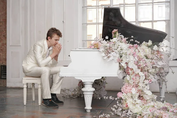 Joven adolescente hombre en depresión con blanco gran piano de cola en el interior solo. chico odia la música y nervioso — Foto de Stock