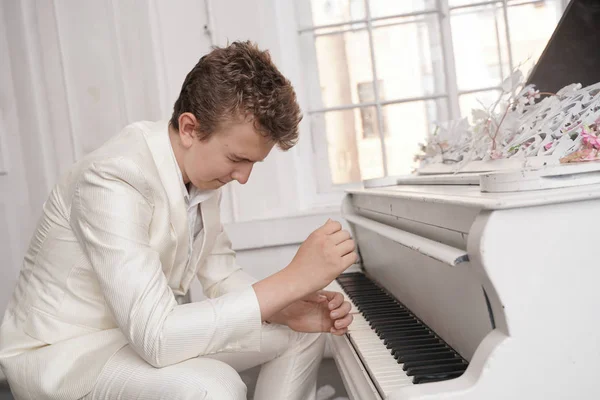 Ung tonåring man i depression med vit stor flygel inomhus ensam. Guy hatar musik och nervös — Stockfoto
