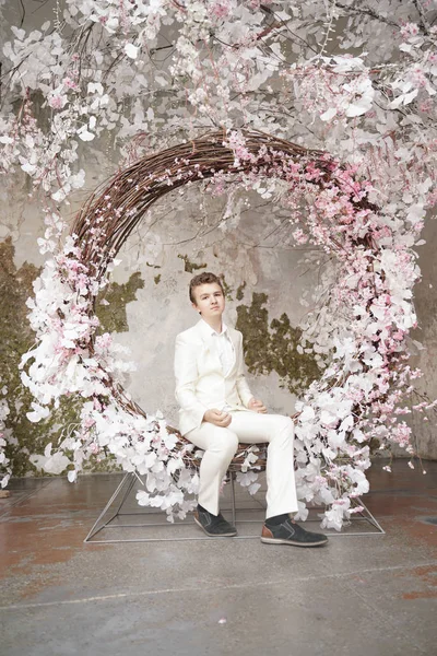 Charmig vacker kaukasiska ung man i en vit Business Suit, jacka och byxor, poserar mot en rosa Sakura. — Stockfoto
