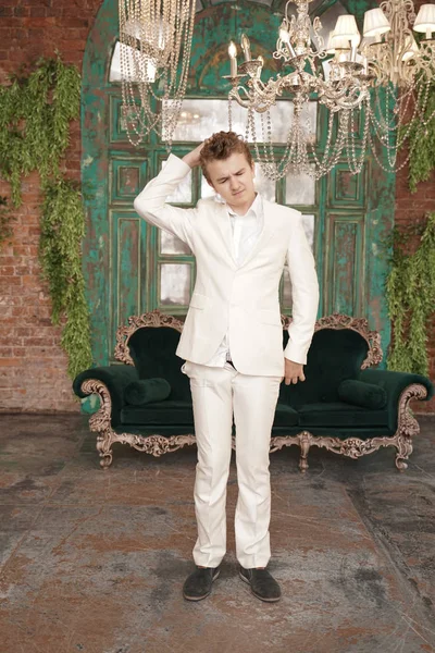 Fashionabla ung man Tonåring i en vit klassisk affärs dräkt på bakgrunden av ett lyxigt rum — Stockfoto