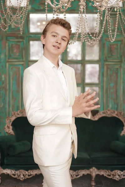 Fashionabla ung man Tonåring i en vit klassisk affärs dräkt på bakgrunden av ett lyxigt rum — Stockfoto