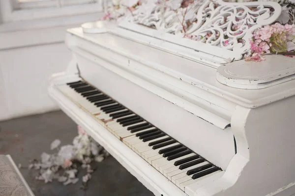 Fehér zongora tavaszi fehér és rózsaszín virágok egy fehér szobában senki — Stock Fotó