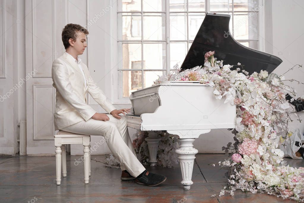 young teenager man with white big grand piano indoors alone enjoys music