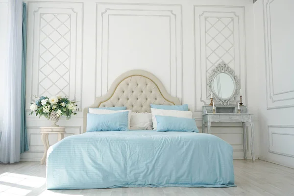 Interior del dormitorio. cama beige con ropa de cama azul en una habitación espaciosa blanca y espaciosa —  Fotos de Stock