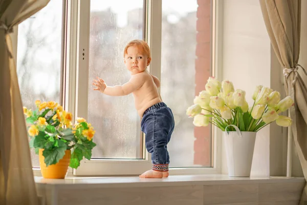 Un petit garçon regarde par la fenêtre . — Photo