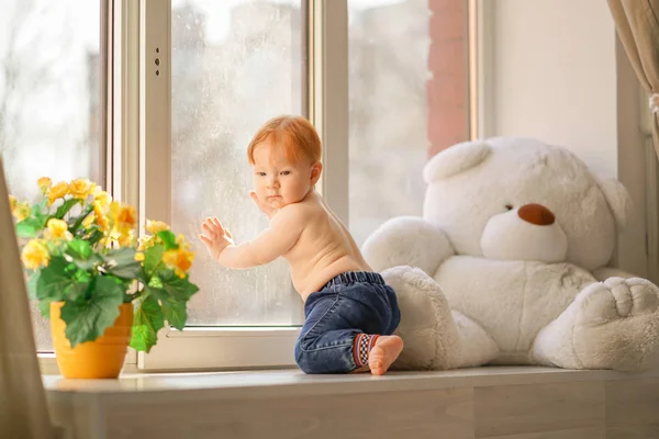 Een kleine jongen kijkt in het venster. — Stockfoto