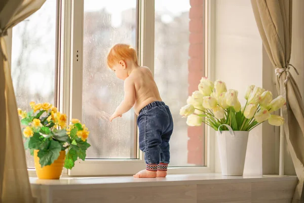 Маленький хлопчик дивиться у вікно . — стокове фото