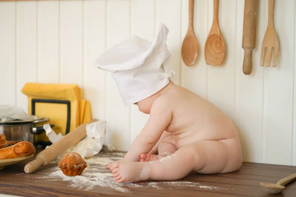 Μικρή φούρναρης στο σεφ Hat στο τραπέζι της κουζίνας και μόνο — Φωτογραφία Αρχείου