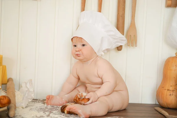 Μικρή φούρναρης στο σεφ Hat στο τραπέζι της κουζίνας και μόνο — Φωτογραφία Αρχείου