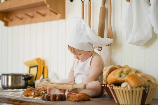 Pequena criança padeiro em chapéu de chef na mesa da cozinha sozinho — Fotografia de Stock