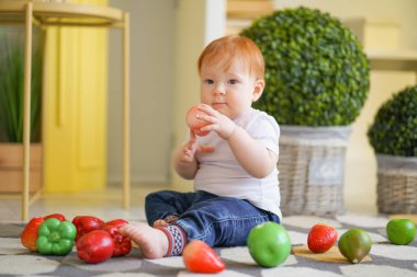 kırmızı saçlı tombul çocuk sebze ile oynar