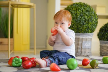 kırmızı saçlı tombul çocuk sebze ile oynar