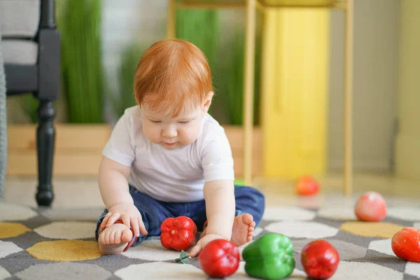 chubby child with red hair plays with vegetables