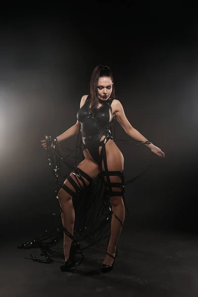 Красивая смесь расы стройные мускулистые танцовщицы девушка позирует в черном купальнике с кожаной упряжкой с видеокассетами — стоковое фото