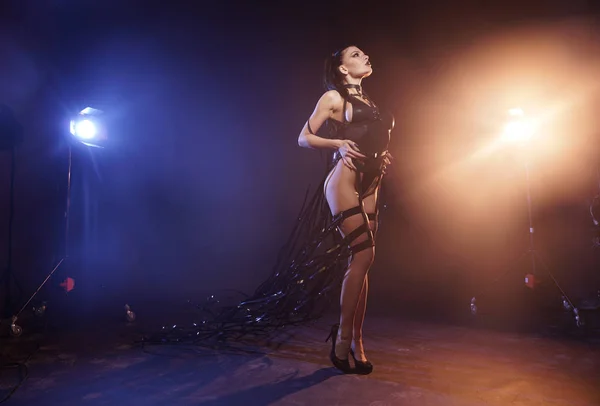 ビデオテープテープ付き革ハーネスで黒い水着でポーズをとる美しいミックスレーススレンダー筋肉ダンサーの女の子 — ストック写真