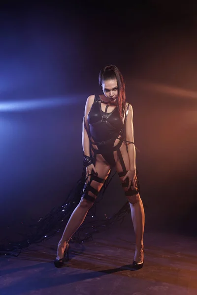 Mooie mix race slanke gespierde danser meisje poseren in een zwart badpak met lederen harnas met videoband tapes — Stockfoto