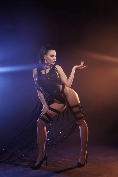 Bella gara mix sottile ragazza ballerina muscolare in posa in un costume da bagno nero con imbracatura in pelle con videocassette — Foto Stock