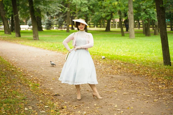 ヴィンテージドレスとレトロな帽子の歩行で若い女性をピンアップの肖像画 — ストック写真