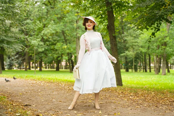 Portrait of pin up young woman in vintage dress and retro hat walking — Stock Photo, Image