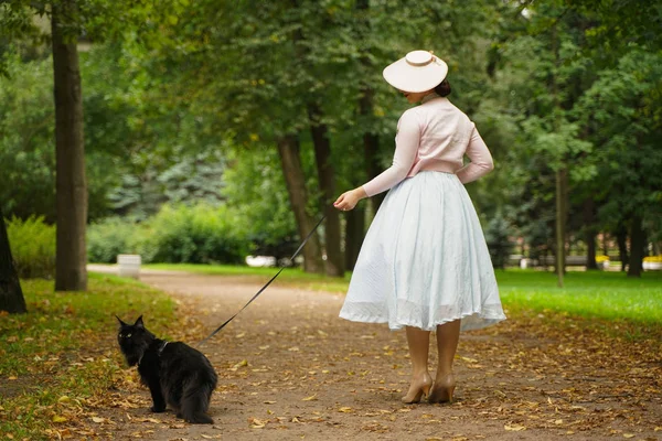Όμορφη vintage γυναίκα περπάτημα με τη μαύρη γάτα Μέιν ρακούν στο πάρκο — Φωτογραφία Αρχείου