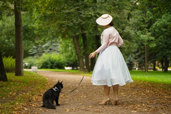 公園で彼女の黒猫メインクーンと歩くかなりヴィンテージ女性 — ストック写真