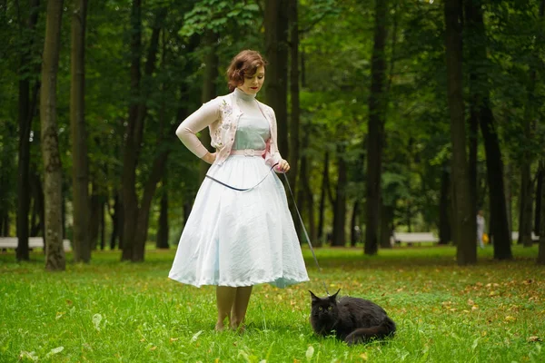 Jolie femme vintage marchant avec son chat noir maine coon dans le parc — Photo