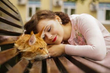 büyük kırmızı maine coon kedi korkutucu ve üzücü. genç sahibi kadın kucaklar ve ilk yürüyüş açık stres onu turuncu evcil hayvan vuruş.