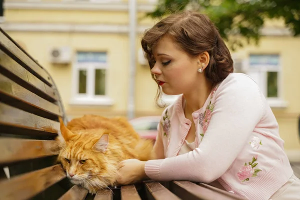 大きな赤いメインクーン猫は怖くて悲しいです。若い所有者の女性は、最初の散歩からストレスで彼女のオレンジ色のペットを抱きしめ、ストローク. — ストック写真