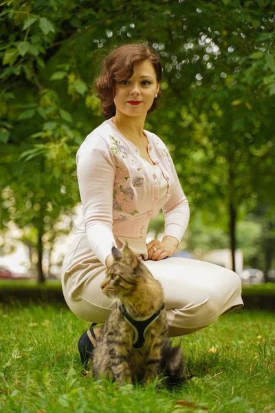 Mulher andando com seu animal de estimação gato casulo maine cinza ao ar livre no parque de verão da cidade . — Fotografia de Stock