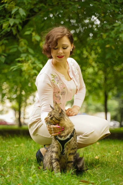 Femme marchant avec son chat chat gris maine coon en plein air dans le parc d'été de la ville . — Photo