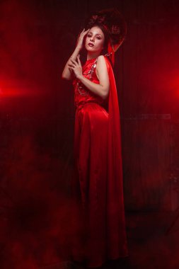 şık uzun kırmızı elbise ve yalnız gece Studio duman arka planda hacimli bir şapka sıkı şık kız. Cadılar Bayramı konsepti.