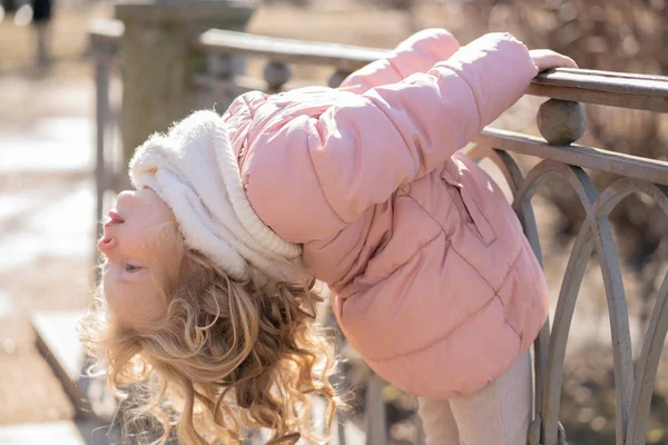 Jolie petite fille en veste rose se promenant dans le parc de la ville de printemps froid seul — Photo