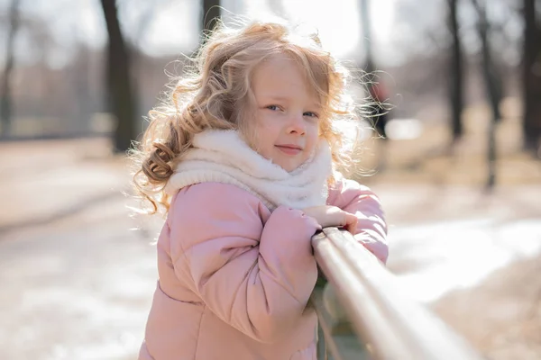 Pretty little girl in pink jacket walking in the cold spring city park alone — Stock Photo, Image