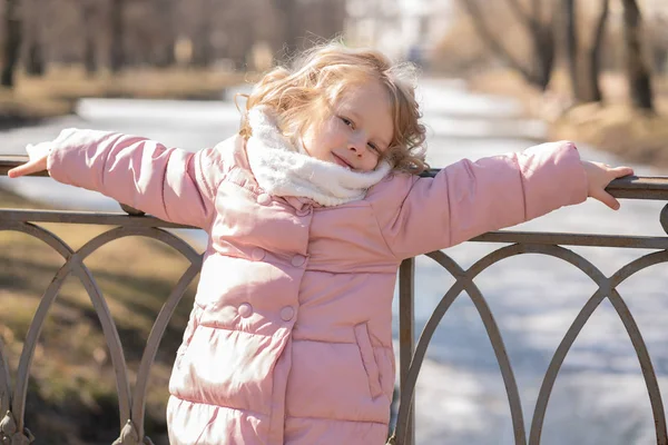 Söt liten flicka i rosa jacka promenader i den kalla våren stadsparken ensam — Stockfoto