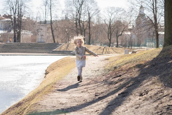 Enfant heureux sauter et courir dans le parc froid de la ville de printemps seul — Photo