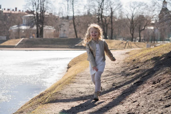Дети счастливые прыжки и бег в холодном весеннем городском парке в одиночку — стоковое фото