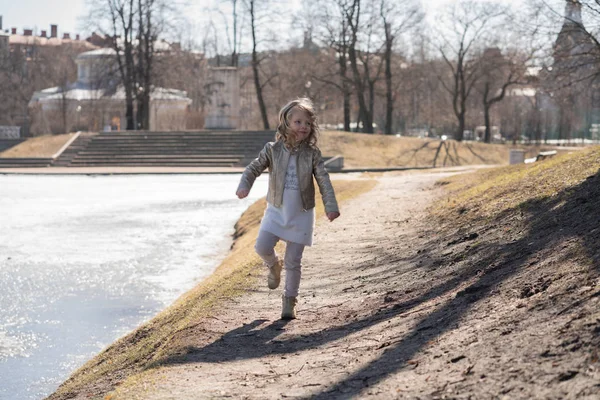 Дети счастливые прыжки и бег в холодном весеннем городском парке в одиночку — стоковое фото