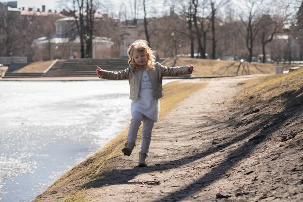 Criança feliz pulando e correndo no frio parque da cidade da primavera sozinho — Fotografia de Stock