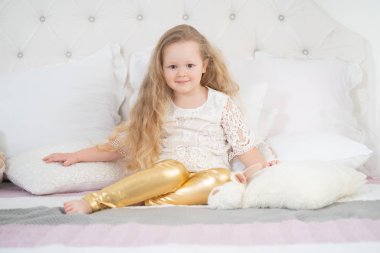 Güzel bir çocuk kız sabahtan hoşlanır. Evde günaydın. Yalnız beyaz yatakta çocuk kız.