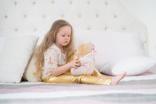 Een leuk kind meisje geniet ochtend. Goedemorgen thuis. Kind meisje op wit bed alleen. — Stockfoto