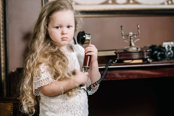 Little grubbler barnflicka pratar på en retro telefon i rummet ensam med sorgsna känslor — Stockfoto