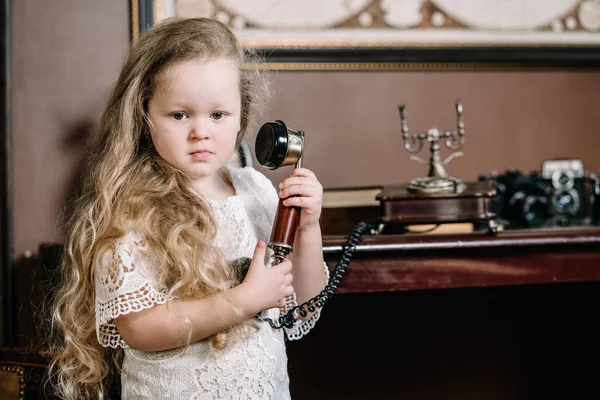 Little grubbler barnflicka pratar på en retro telefon i rummet ensam med sorgsna känslor — Stockfoto