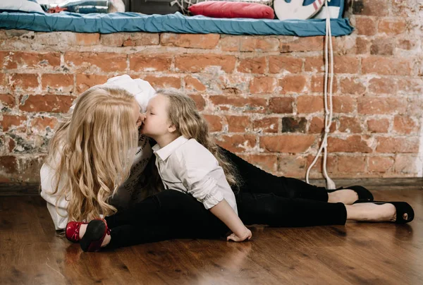 Little girl and her mother woman relaxing and enjoying by sitting on the floor in their loft style apartment with red brick walls — Stock Photo, Image