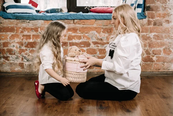 Pretty blonde mother and her caucasian little daughter sitting on the floor with big box gift and happy together — Stock Photo, Image